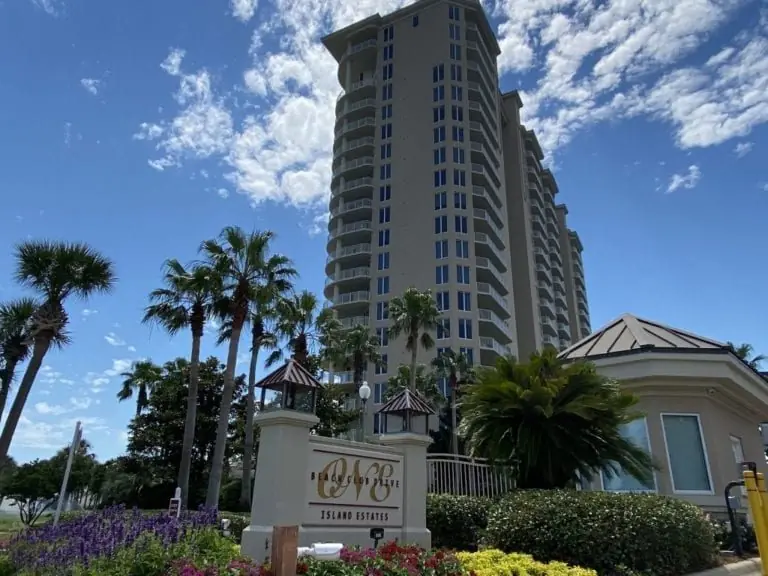 One Beach Club Drive during envelope restoration, showing exposed balcony edges and staged repair work, Miramar Beach, Florida.